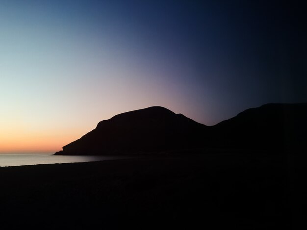 Закат с силуэтом горы на пляже