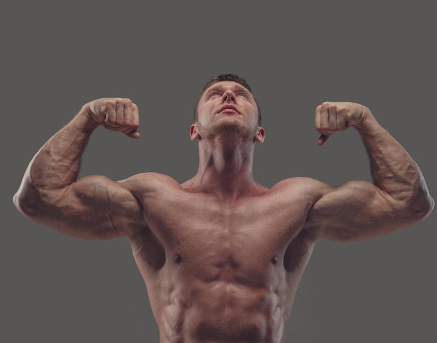 Foto gratuita modello maschile fitness senza camicia abbronzato isolato su sfondo grigio.