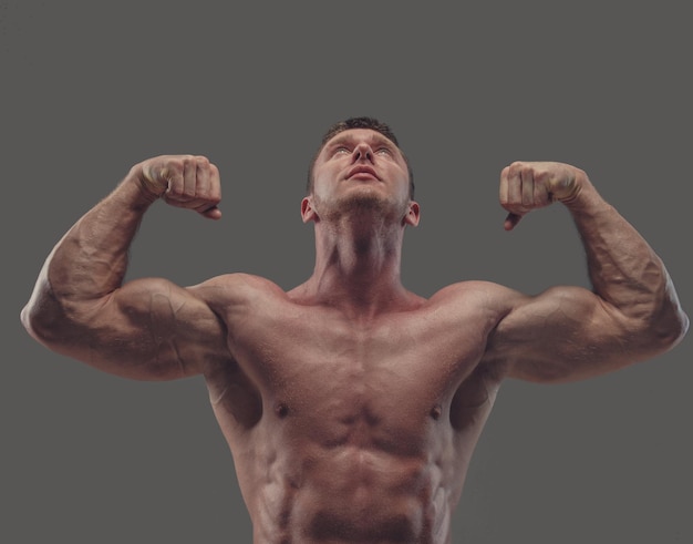 Free photo suntanned shirtless fitness male model isolated on a grey background.