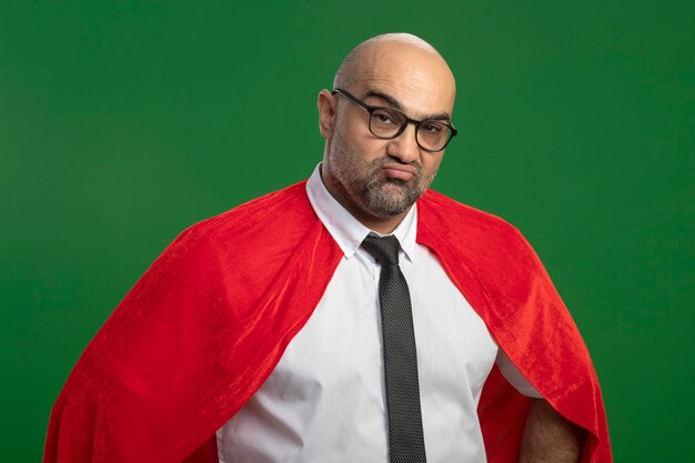 Бесплатное фото Бизнесмен супергероя в красной накидке и очках недоволен