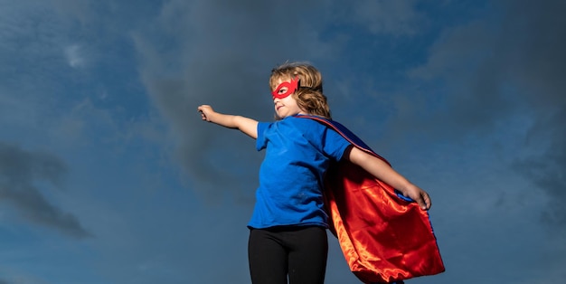 劇的な青い空を背景にしたスーパーヒーローの子供スーパーパワーを持つ強力なスーパーヒーローの少年