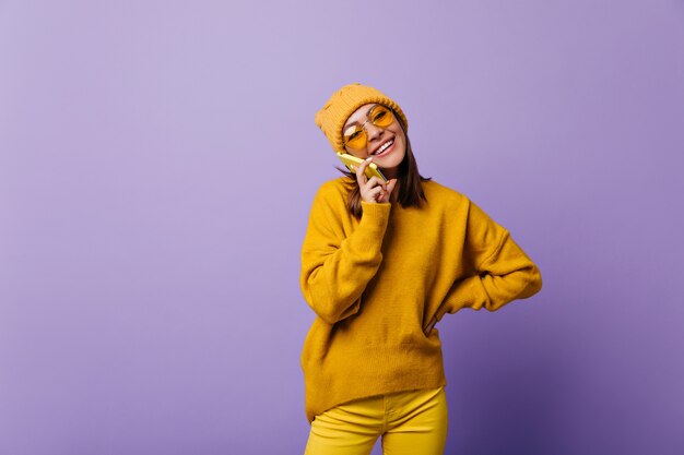 Superior wonderful active girl in yellow total look speaking by her phone with cheerful mood. Portrait of 24 year model