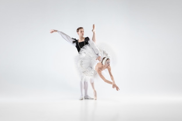 Supporting. Graceful classic ballet dancers dancing isolated on white studio background. Couple in tender clothes like a white swan characters. The grace, artist, movement, action and motion concept.