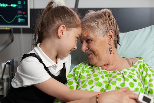 Sostenere la nipote che tocca la fronte con la nonna anziana che mostra amore durante la rec...