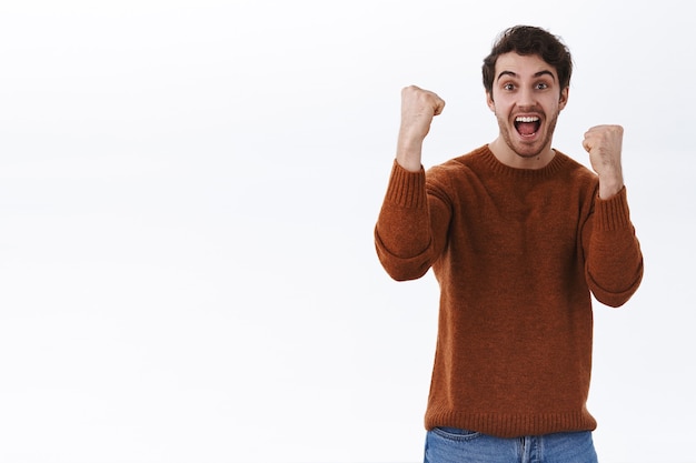 Free photo supportive and enthusiastic, excited young man rooting for favourite team, raising hands up