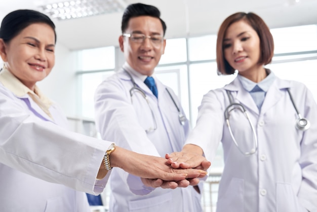 Supportive medical coworkers stacking hands to show collaboration is the key to success