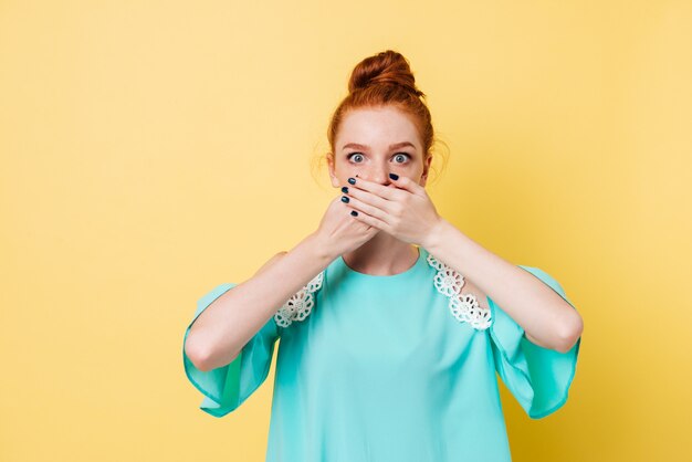 Suprised ginger woman covering her mouth and looking