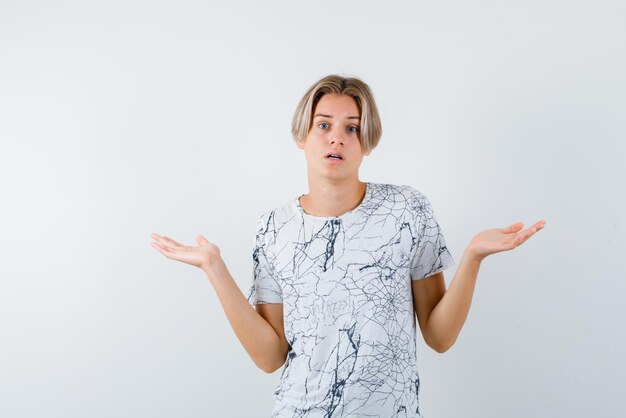 The suprised teenage boy is opening wide his hands on white background