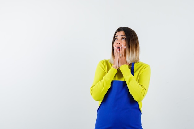 The suprised woman is holding her hands on chin on white background