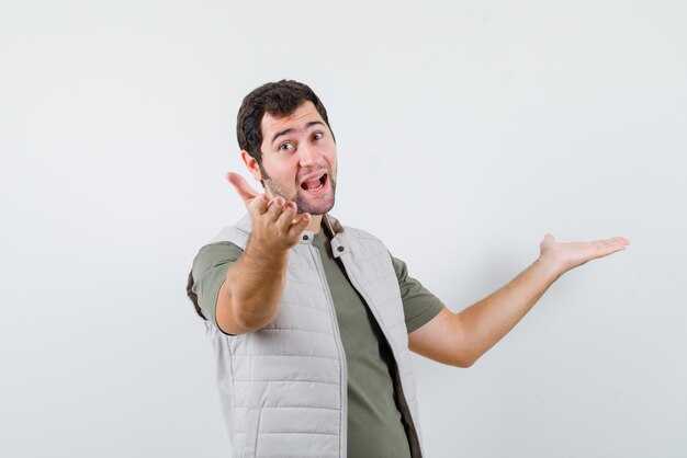 The suprised young boy is opening wide his hands on white background