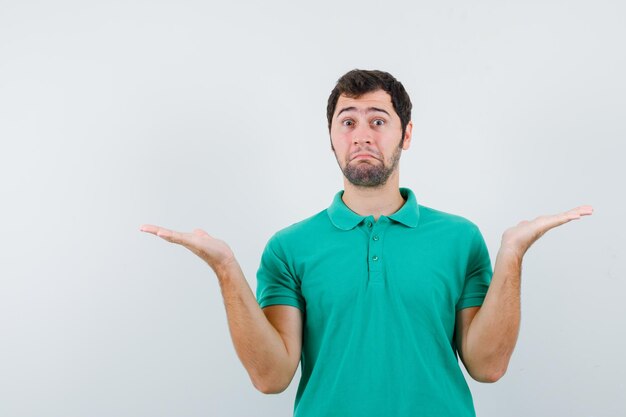 The suprised young man is opening wide his ahnds on white background