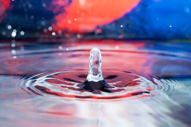 Surface with water drop falling and colorful background