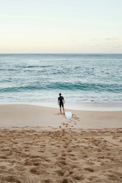 Foto gratuita uomo del surfista che esamina il colpo lungo verticale del mare