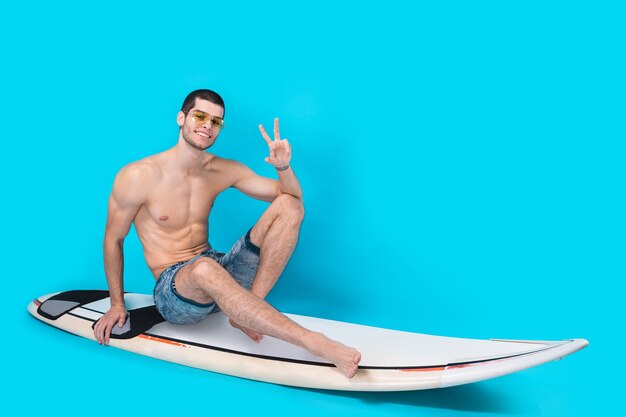 Surfer man posing showing victory sign