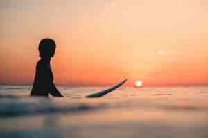 Free photo surfer on the ocean with the breathtaking sunset in the sky in the background