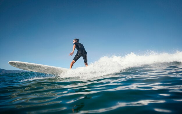 Surfer riding wave in daylight long view