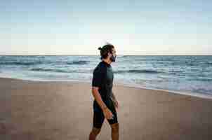 Free photo surfer walking alongside the ocean