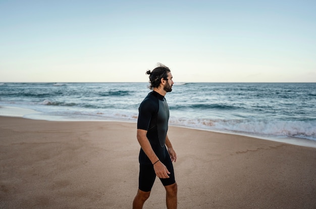 Surfer walking alongside the ocean