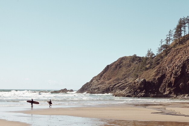 Серферы вдалеке на каменистом пляже