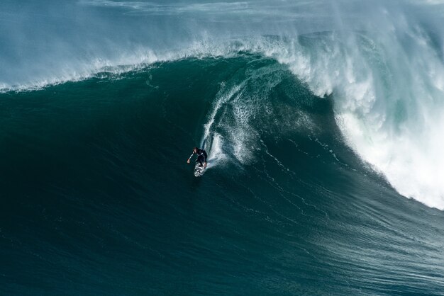 ポルトガル、ナザレの海岸に向かって大西洋の波に乗っているサーファー