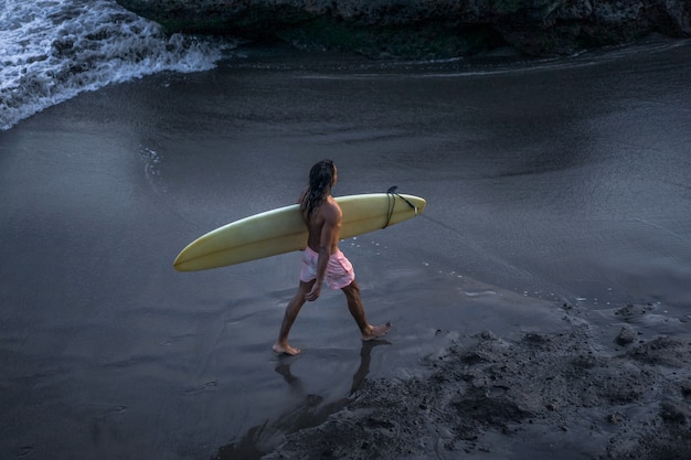 Foto gratuita i surfisti al tramonto percorrono l'oceano con una tavola da surf.