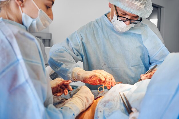 클리닉에서 복부 성형 수술을 수행하는 외과의 및 조수