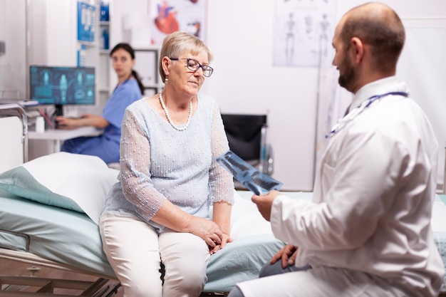 Surgeon discussing about treatment with senior woman in examination room