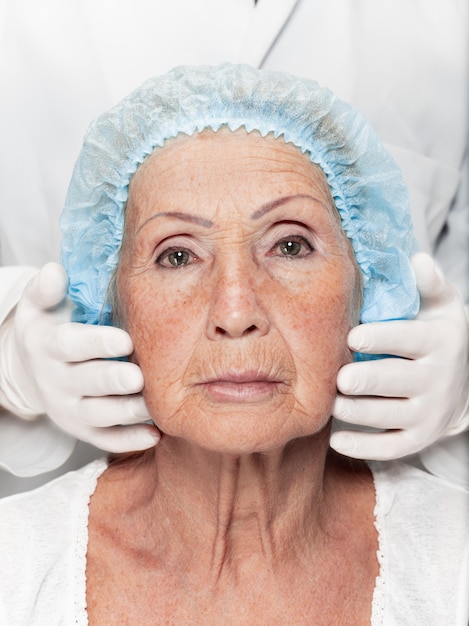 Хирург делает проверку кожи на женщину среднего возраста перед пластической операцией