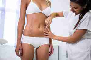 Free photo surgeon drawing lines on womans abdomen for liposuction and cellulite removal