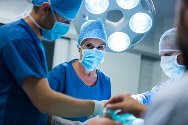 Surgeon looking at camera while colleague performing operation in operation room