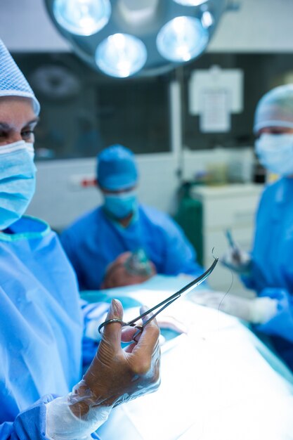 Хирург смотрит на режут ножницами в комнате операции