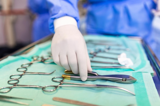 Surgeon picking up surgical tool from tray surgeon is preparing for surgery in operating room he is in a hospital