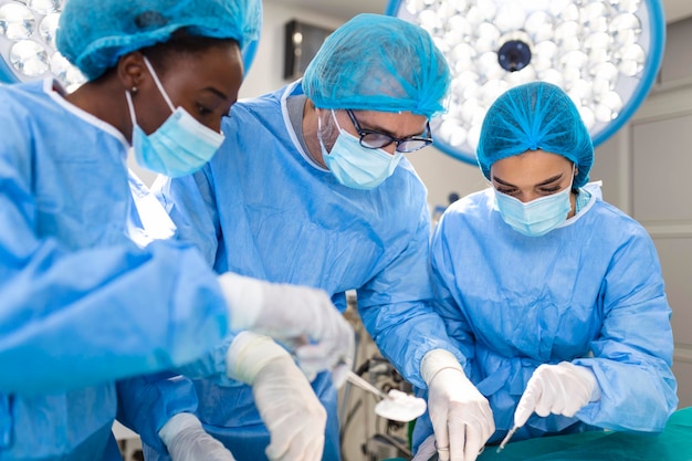 제복을 입은 외과 의사 팀은 심장 수술 클리닉에서 환자를 수술합니다. 현대 의학 전문 외과 의사 팀