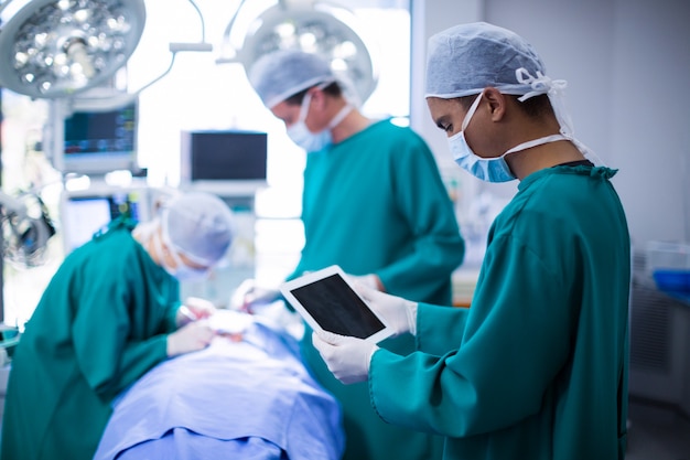 Хирург с помощью цифрового планшета в операционном зале