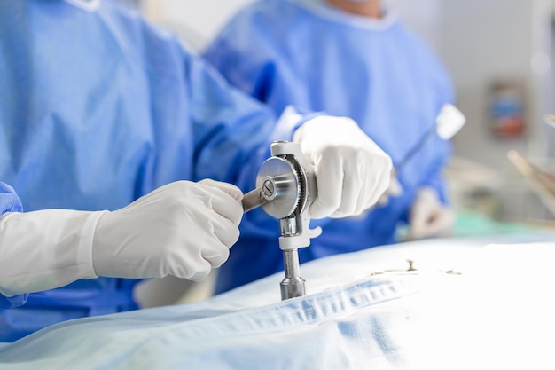 Бесплатное фото Хирурги закрывают руки во время операции хирург с помощью дрели во время процедуры врачи носят защитную спецодежду в операционной