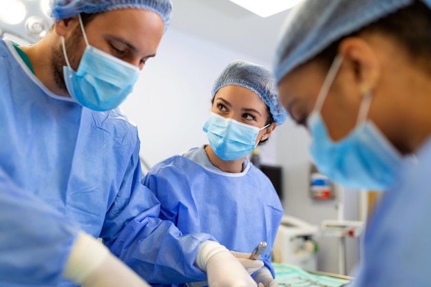 가벼운 수술실에서 외과 의사가 성형 수술을 수행합니다. 남녀 의사 팀이 재건 수술을 수행합니다.
