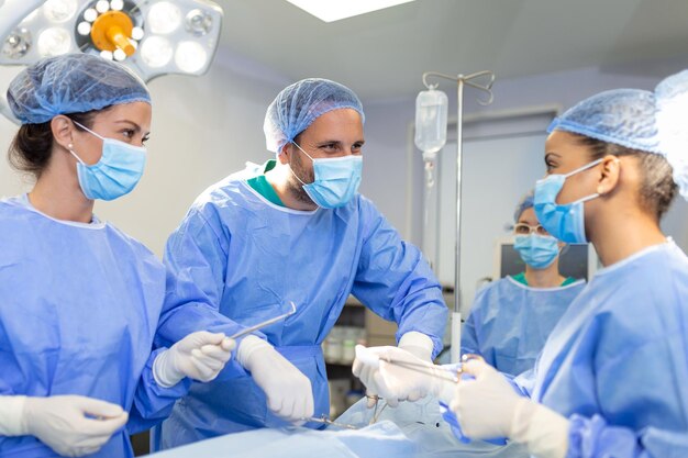 수술대에서 수술하는 동안 한 팀의 외과의사 남녀가 종양학 수술을 수행합니다.