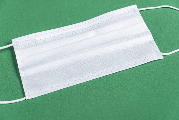 Surgical mask over minimalist green background