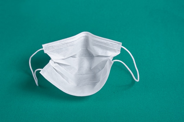 Surgical mask over minimalist green background