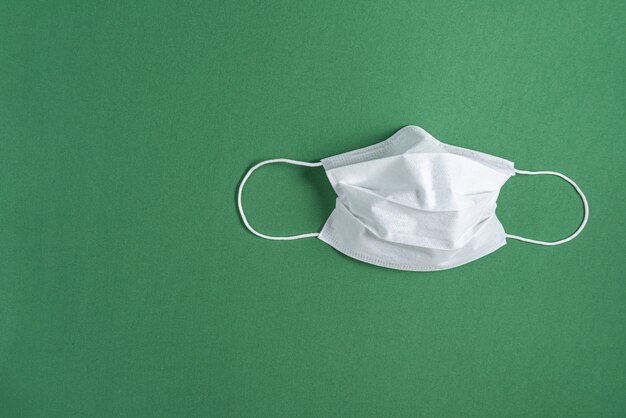 Surgical mask over minimalist green background