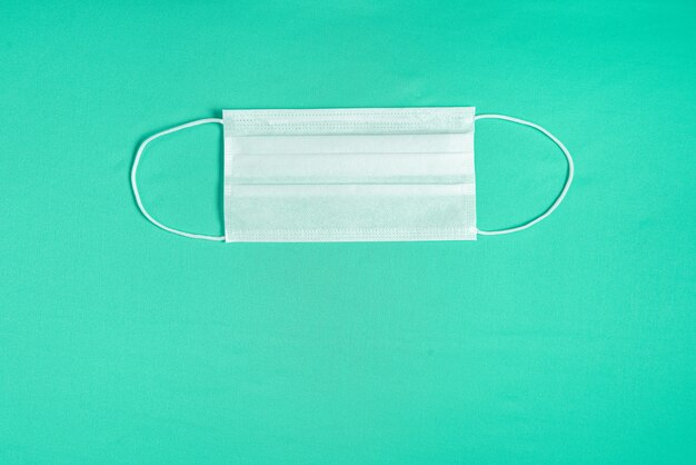 Surgical mask over minimalist green background