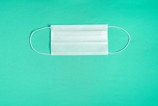 Surgical mask over minimalist green background