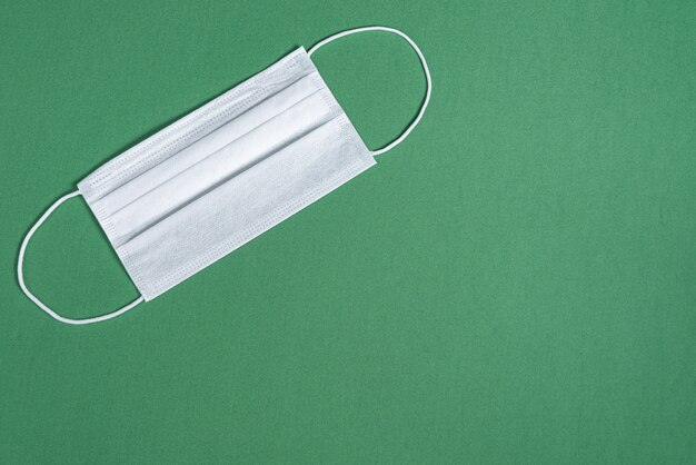 Surgical mask over minimalist green background