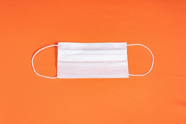 Surgical mask over minimalist orange background