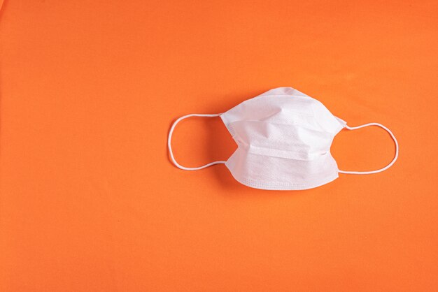 Surgical mask over minimalist orange background