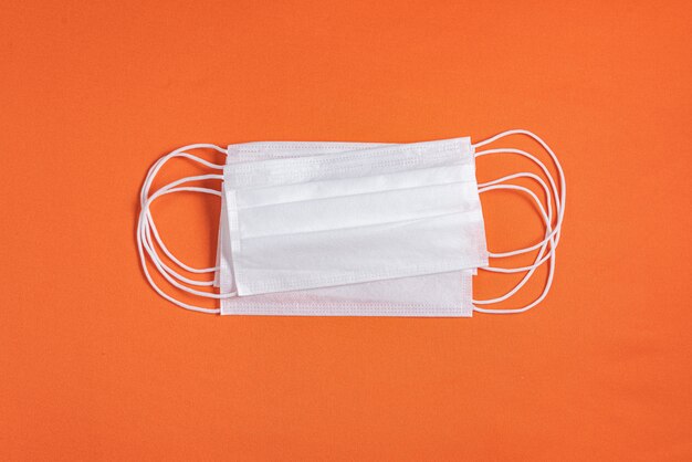 Surgical mask over minimalist orange background