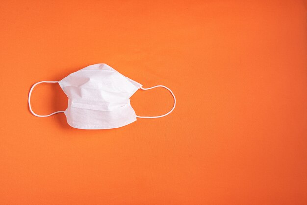 Surgical mask over minimalist orange background