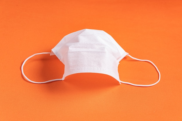 Surgical mask over minimalist orange background