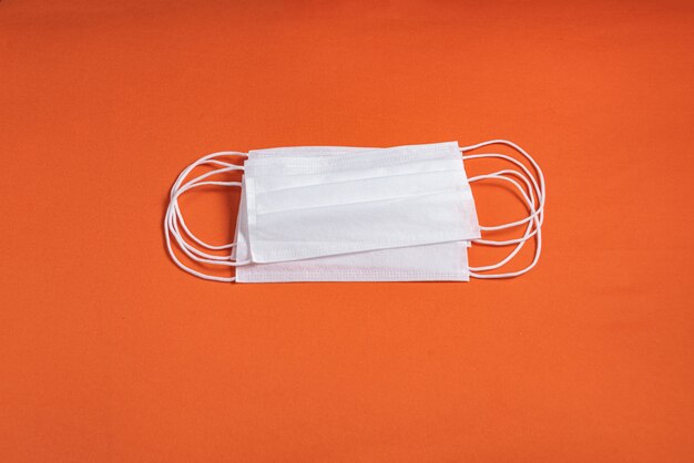 Surgical mask over minimalist orange background