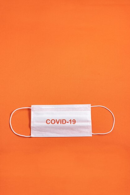 Surgical mask over minimalist orange background